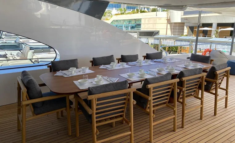 Outdoor dining area on 2024 Azimut Magellano 30M yacht with elegant wooden table and chairs.